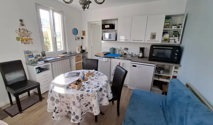 La kitchenette : placards blancs, micro-ondes, mini-four, lave-vaisselle et table ronde