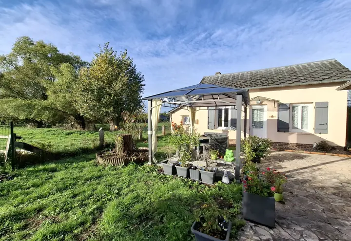 La petite maison aux volets bleus, sa tonnelle et son jardin fleuri