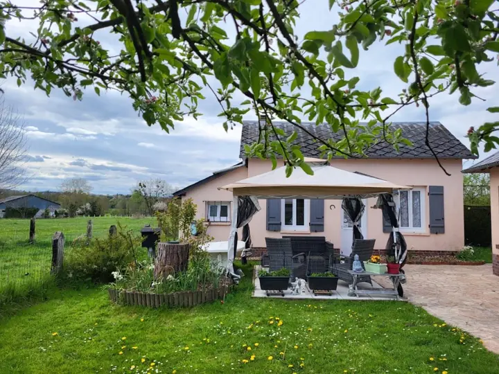 La maison vue du jardin, sous les branches d’un pommier, avec les champs à l’arrière-plan